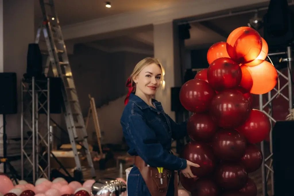 an event decorator arranging red balloons in an event space