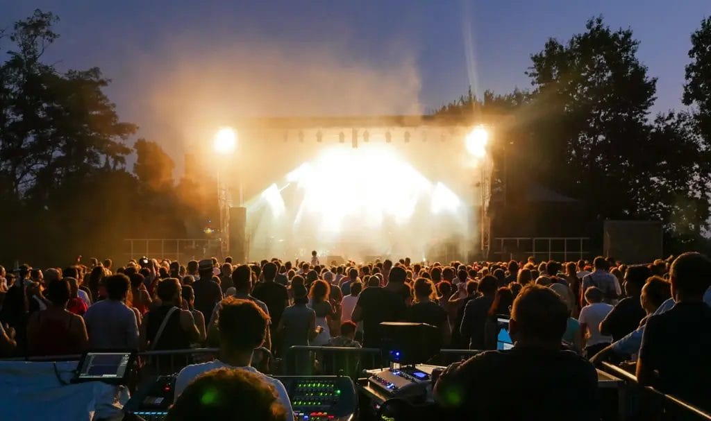 A crowd at a festival watching a performance on stage.