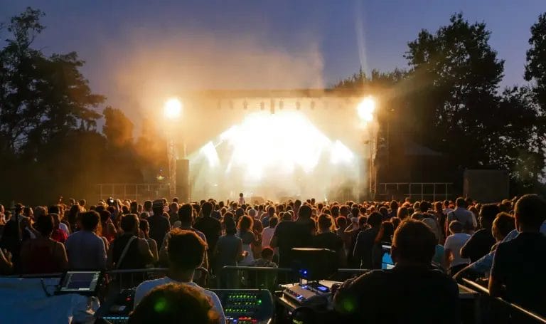 A crowd at a festival watching a performance on stage.