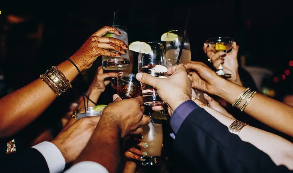 A group of wedding guests holding their glasses up in a large toast.