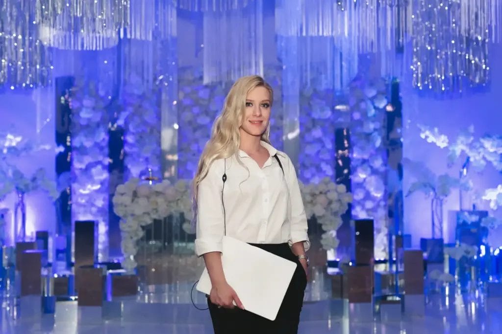 Event planner with clipboard standing in front of decorated stage