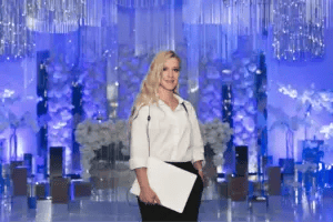 Event planner with clipboard standing in front of decorated stage