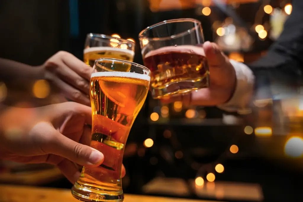 friends drinking beer and clinking glasses at a pub.