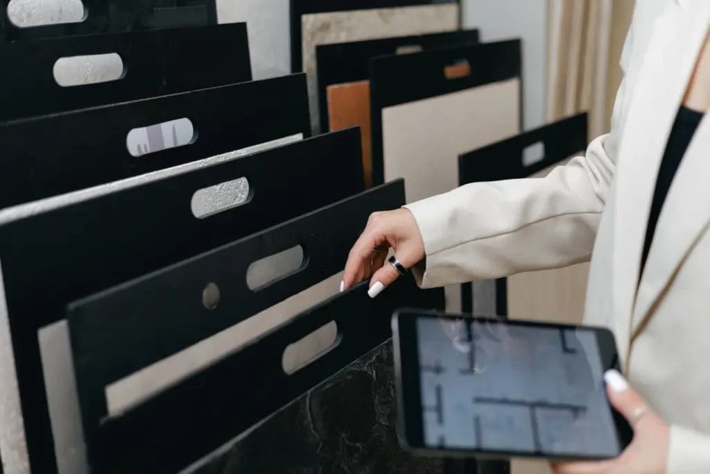 Close-up of an interior designer comparing flooring samples while looking at a floor plan on her tablet.