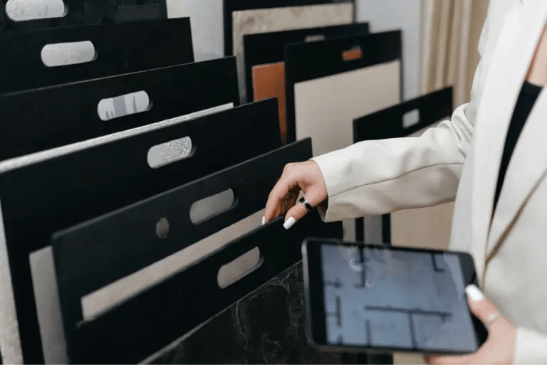 Close-up of an interior designer comparing flooring samples while looking at a floor plan on her tablet.