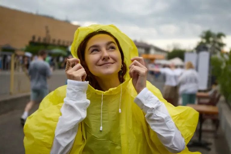 a young woman smiling while wearing a rain poncho at an outdoor event